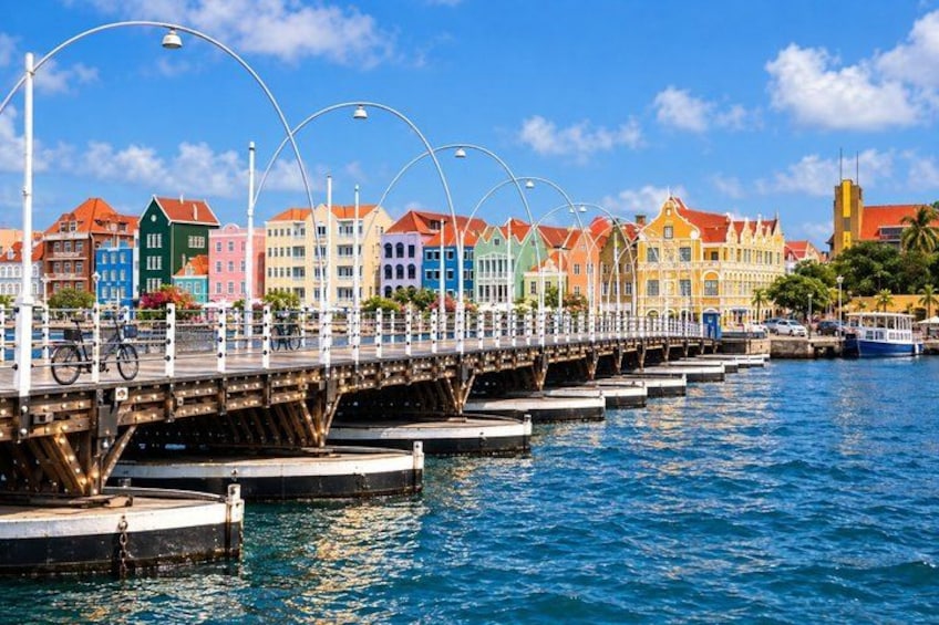 A colorful waterfront promenade with a bridge, buildings, and boats. 2