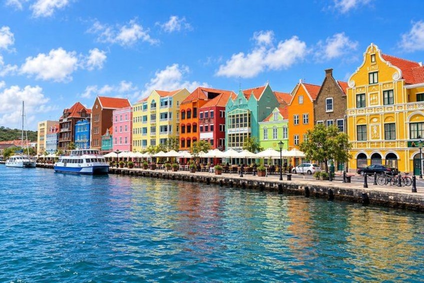 A waterfront with colorful buildings, a boat, and a clear blue sky. 3