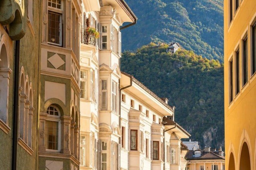A row of historic buildings with ornate facades, a mountain in the background, and a clear sky. 2