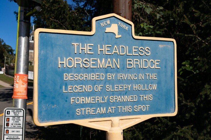 A blue sign with white text describing The Headless Horseman Bridge, located in New York. 1