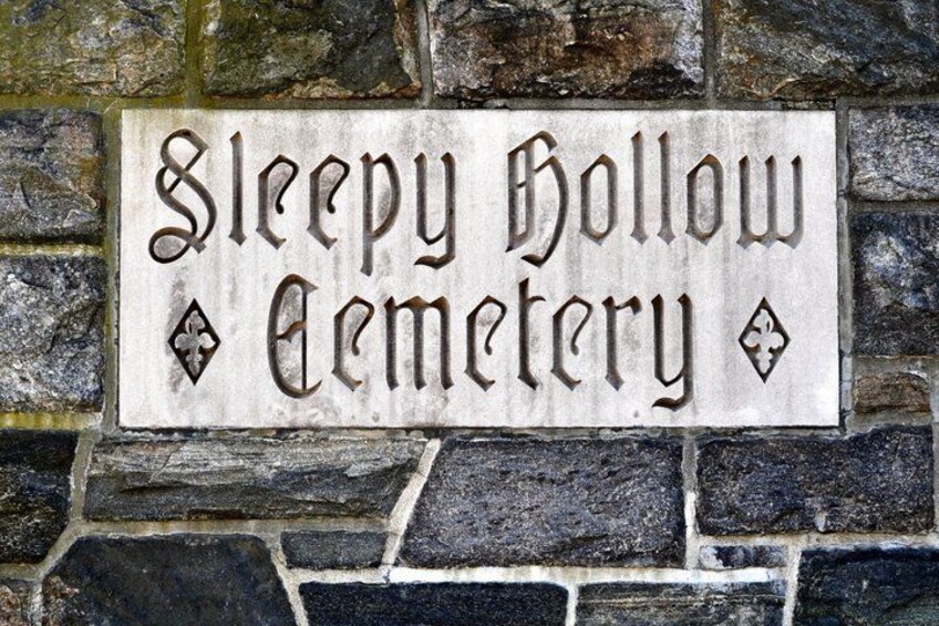 A stone wall with a sign that reads 'Sleepy Hollow Cemetery.' 5