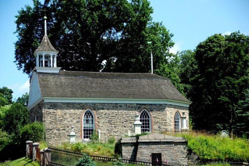 A stone church with a bell tower, surrounded by greenery. 3