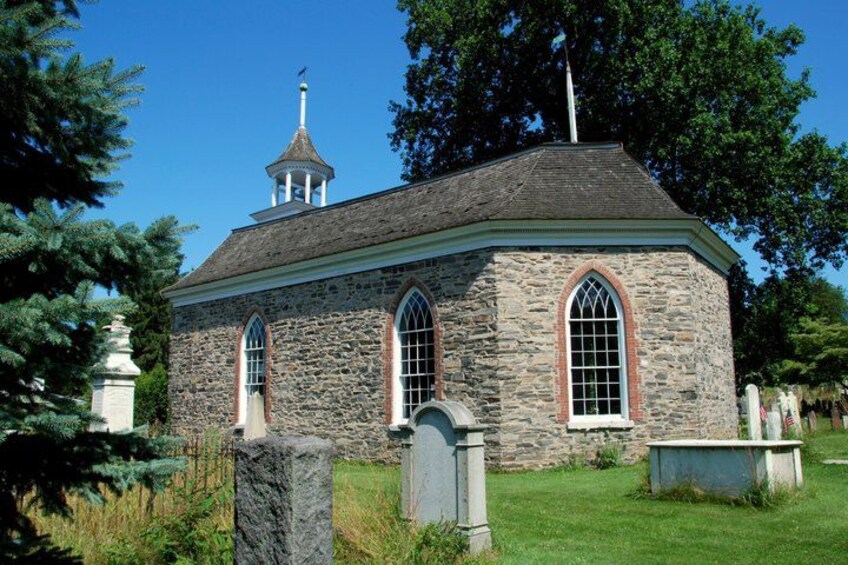 A stone church with a steeple, arched windows, and a small bell tower. 4