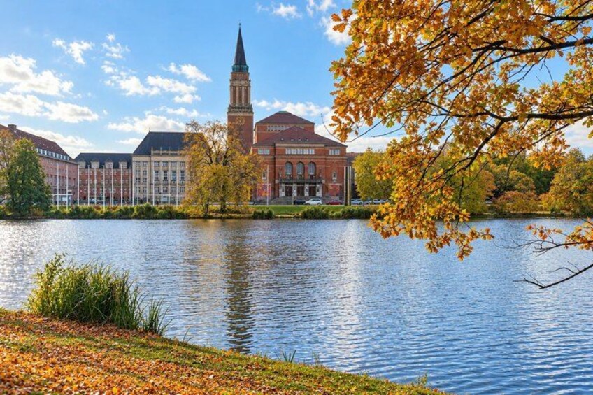 A lake with a red brick building and a tower in the background. 5