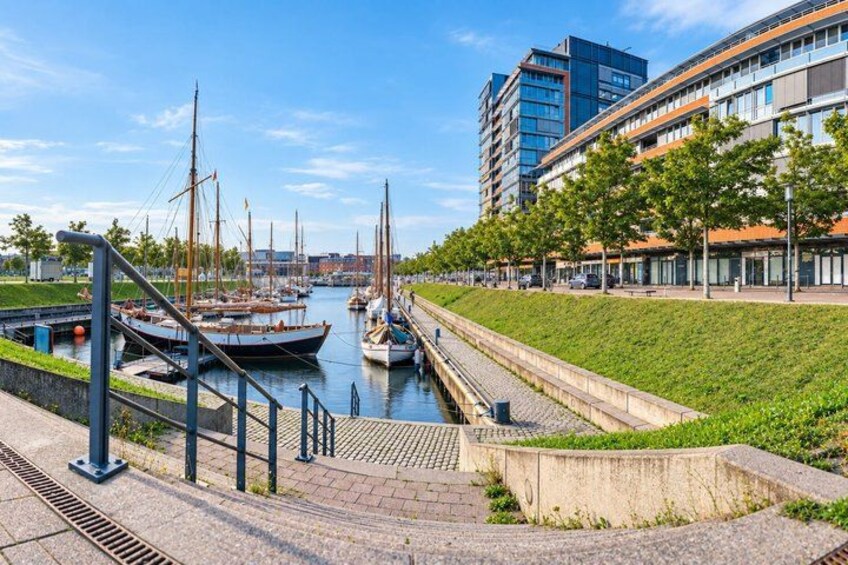 A canal with boats, a grassy embankment, and modern buildings in the background. 3