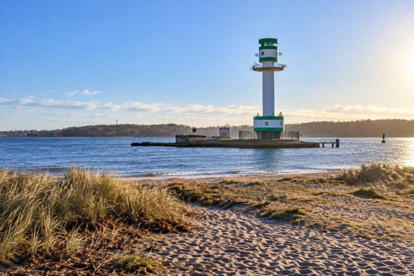 A lighthouse on a sandy beach with water in the background. 2