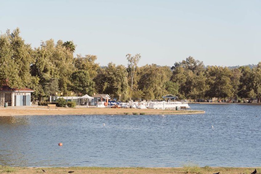 A lake with a boat dock, a small building, and trees in the background. 2