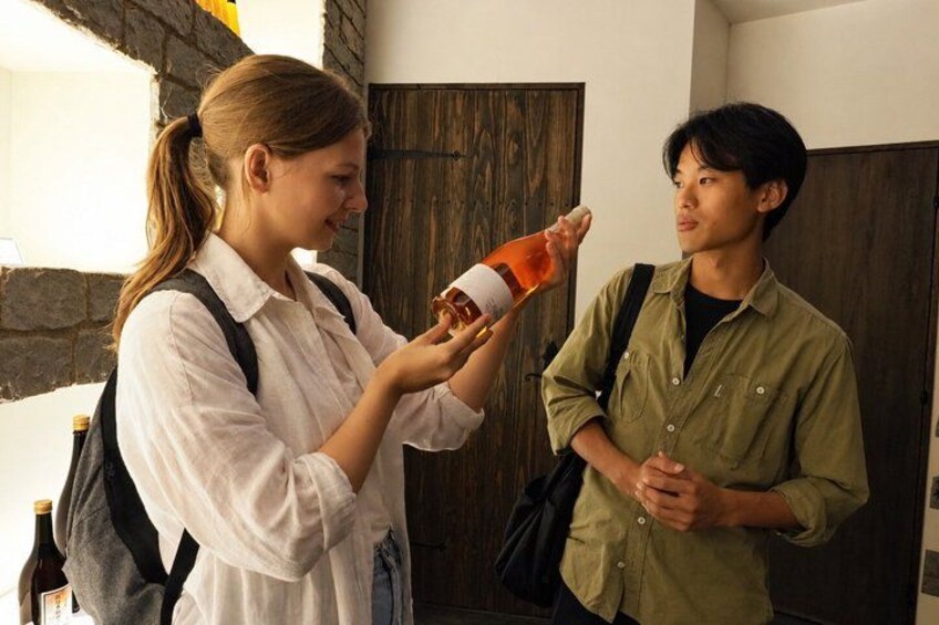 Two people standing indoors, one holding a bottle. 5