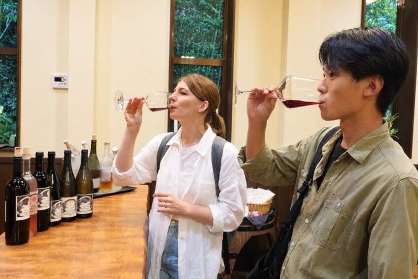 Two people tasting wine at a tasting event with various bottles on a table. 1