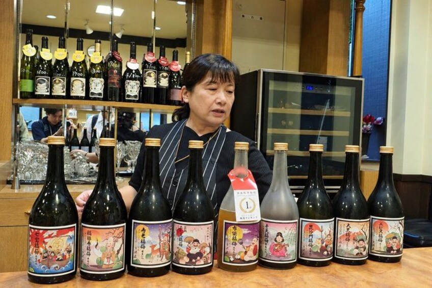 A person seated at a table with various bottles of sake. 3