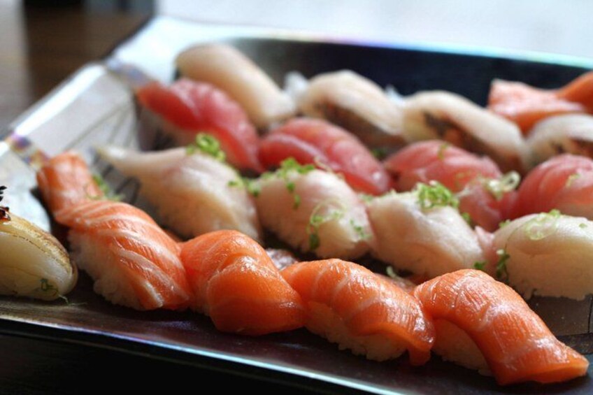 A variety of sushi on a tray, including salmon and white fish varieties. 4
