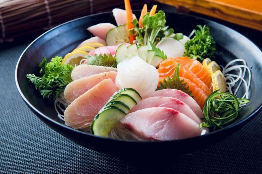 A bowl of sashimi with various fish slices, cucumber, and green onions. 2