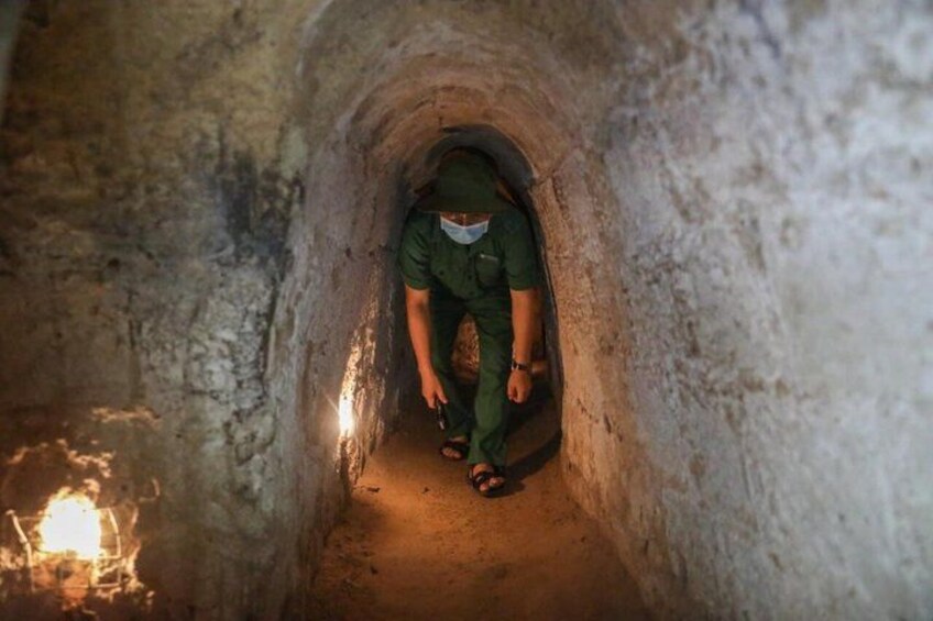 A person in a narrow tunnel with rough walls and a light source at the end. 3