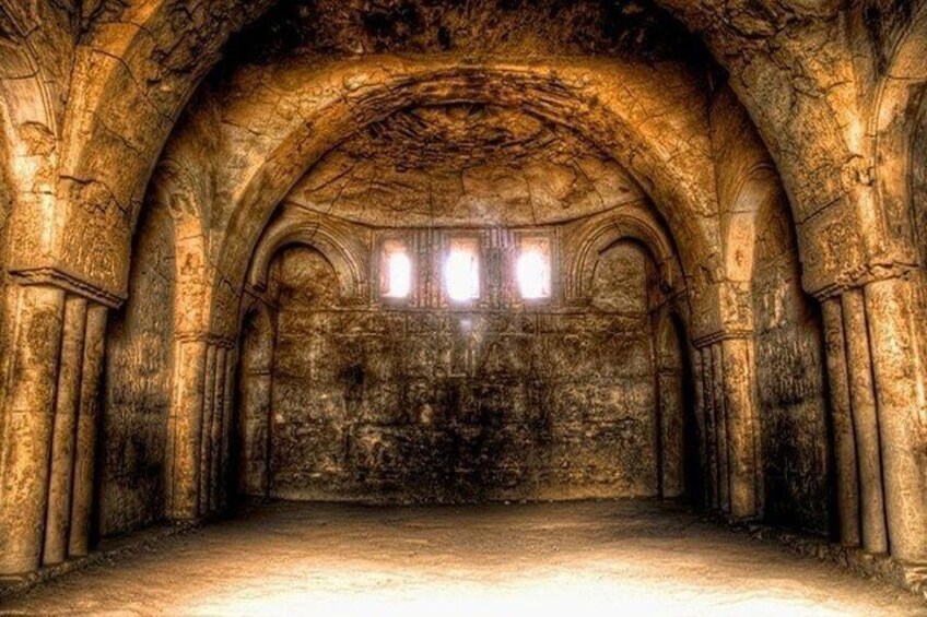 An ancient stone structure with arched ceilings and columns. 5