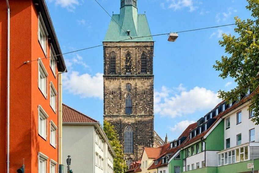 A historic tower with a green roof, surrounded by colorful buildings. 5