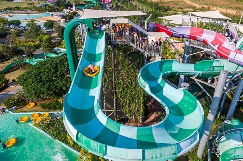 A water park with a large green and white water slide, a red and white slide, and a pool area. 4