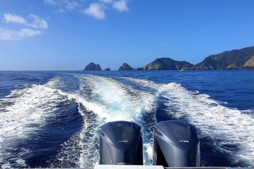 A boat's wake in the ocean with mountains in the background. 3
