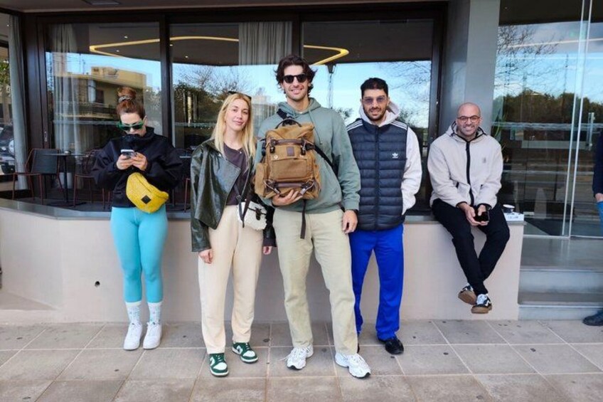 A group of people standing in front of a building with large windows. 2