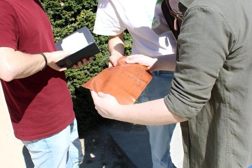 A person holding a brown paper bag and a black box. 3
