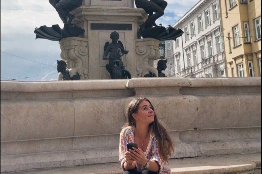 A person sitting on steps in front of a fountain with sculptures. 4