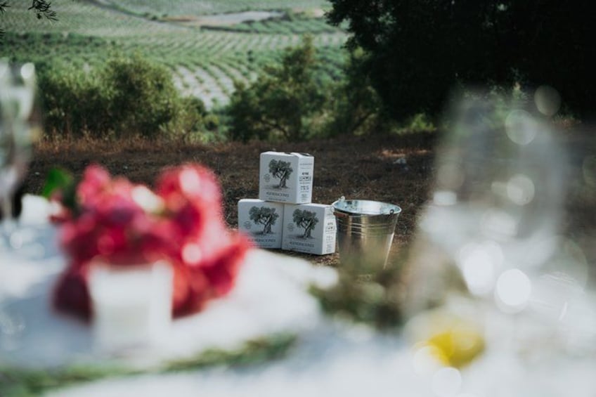 A table with a bouquet of flowers, a metal bucket, and a box with a tree design. 1