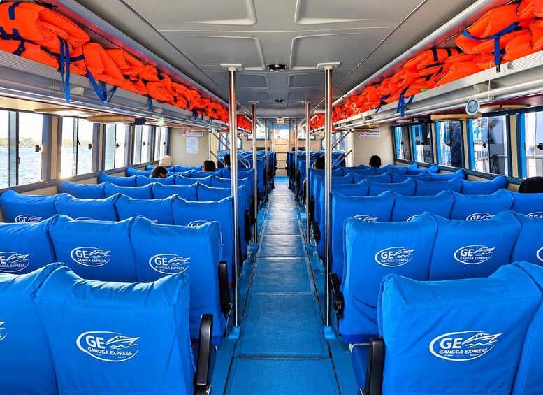 A bus interior with blue seats and orange life jackets on the ceiling. 1
