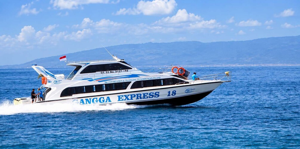 A boat named 'ANGGA EXPRESS 18' with a flag, lifebuoys, and a mountainous landscape in the background. 2