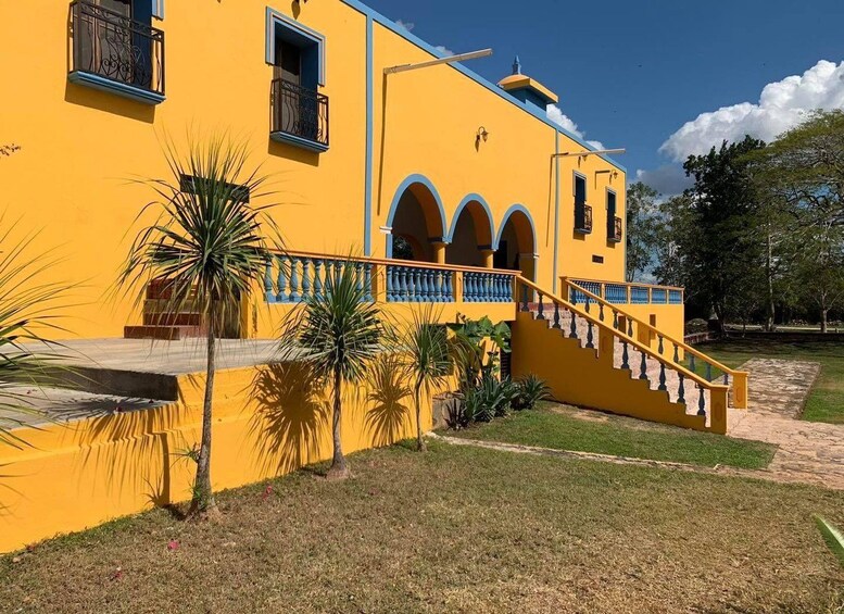 A yellow building with blue accents, a staircase, and palm trees. 5