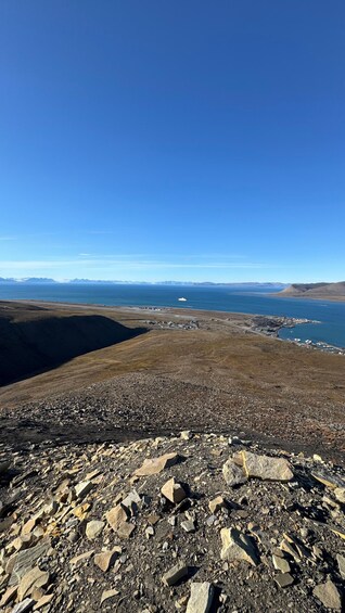 Un paysage rocheux offrant une vue sur une zone côtière et sur des montagnes lointaines, le tout sous un ciel bleu dégagé. 2