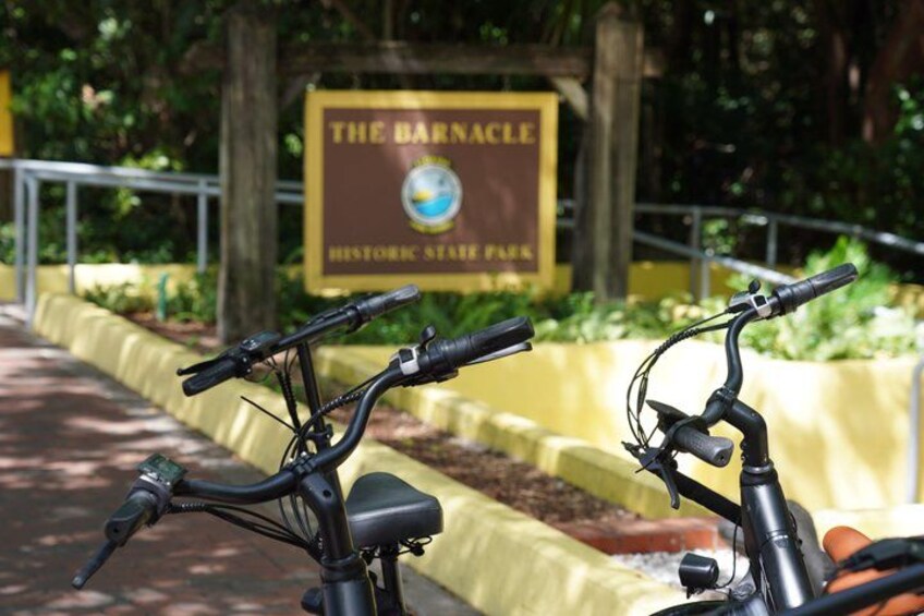 A bicycle parked in front of a sign for The Barnacle Historic State Park. 1