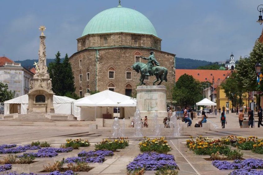 A historic building with a dome, a statue, and a fountain in a public square. 5