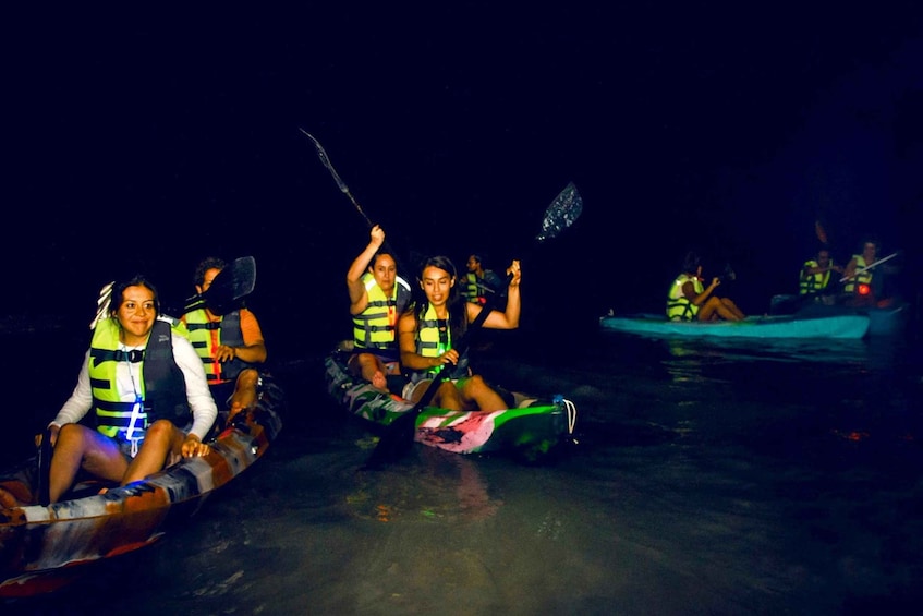 People in a boat wearing life jackets, paddling at night. 5