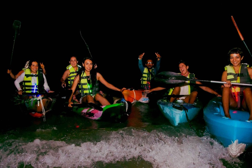 People in small boats on a body of water at night. 1
