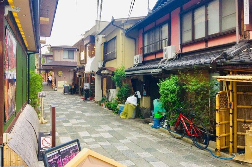 A narrow alley with traditional buildings, a bicycle, and a checkered pavement. 3