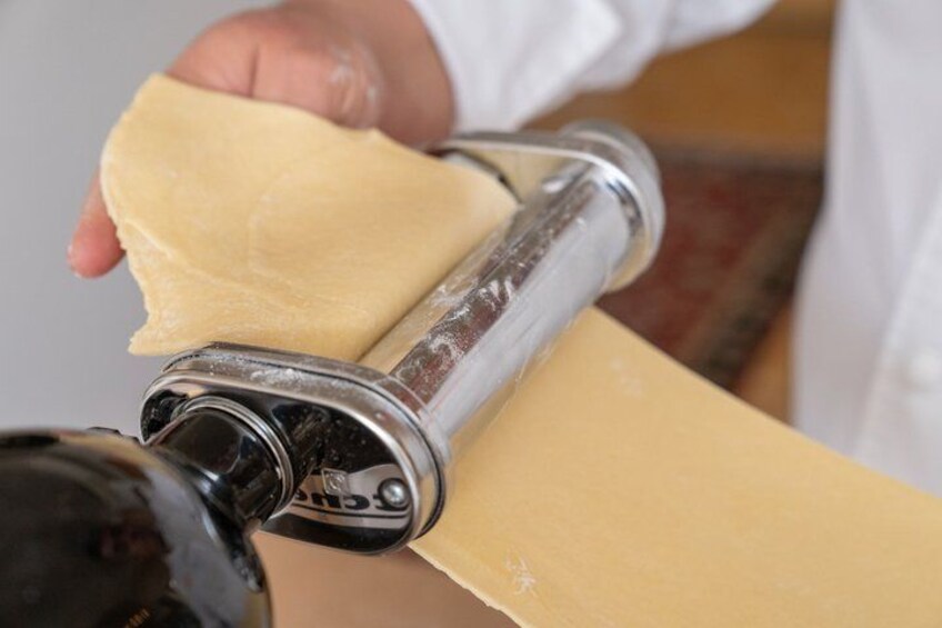 A person using a rolling pin to flatten dough on a surface. 4