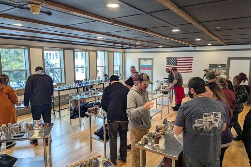 An indoor event with people standing at tables, an American flag, and a window view. 2