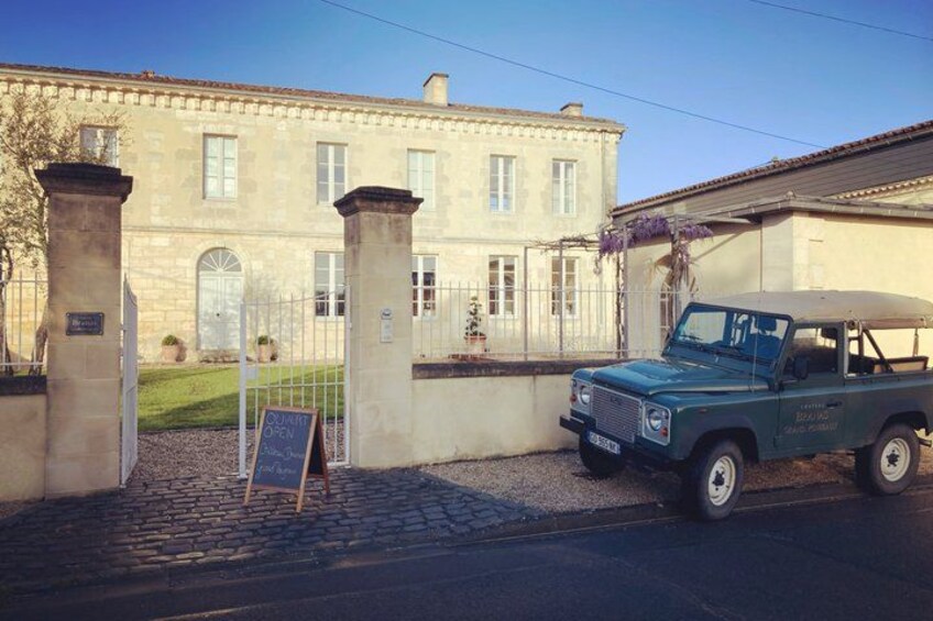 A stone building with a parked blue vehicle in front. 1