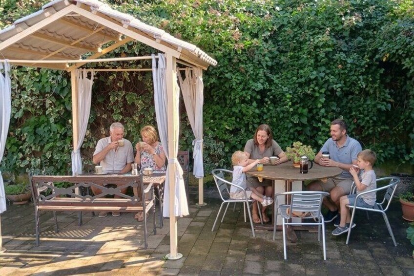 A family dining under a gazebo in a garden. 2