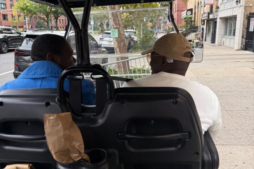 Two people in a vehicle, one wearing a blue jacket and the other a white shirt and cap. 3