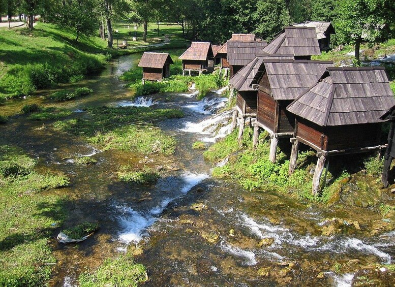 A river with wooden structures on stilts, surrounded by greenery. 3