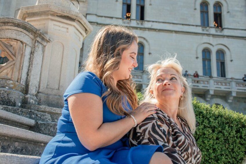 Two people sitting on steps in front of a building with classical architecture. 4