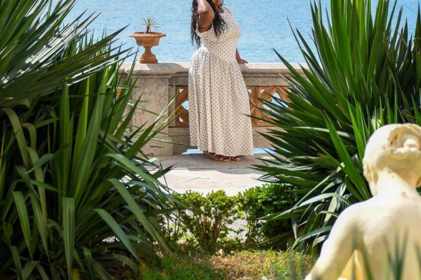 A person in a polka dot dress standing on a stone platform with a view of the sea. 5