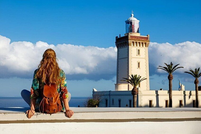 A person sitting on a ledge with a lighthouse in the background. 2