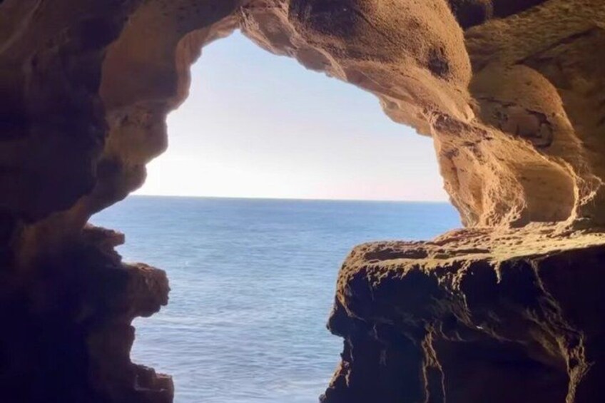 A natural rock formation with a cave-like opening leading to a body of water. 5