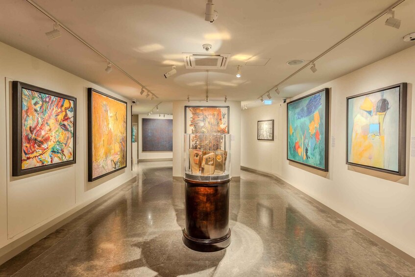 An art gallery with abstract paintings on the walls and a central sculpture. 3