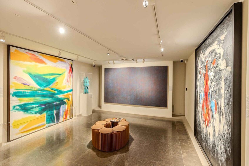 An art gallery with abstract paintings on the walls and a central seating area. 2