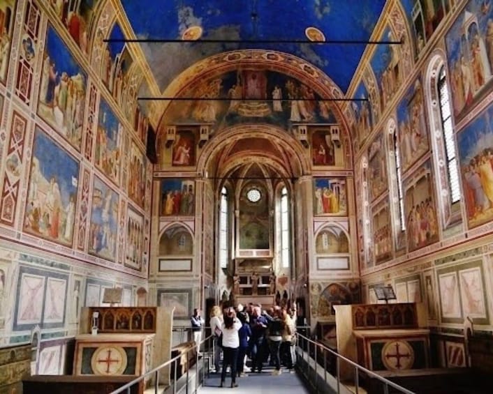 An interior of a church with frescoes, arches, and a group of people. 4