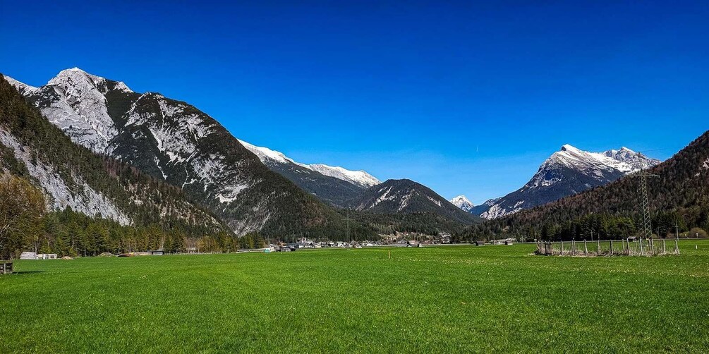 A mountainous landscape with a green field in the foreground and snow-capped peaks in the background. 2