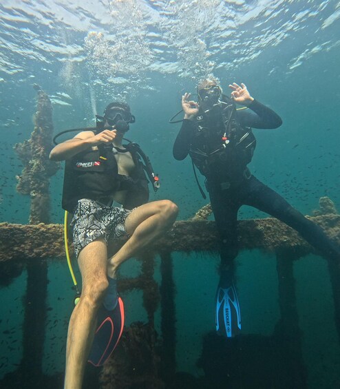 Two scuba divers underwater near a shipwreck. 5