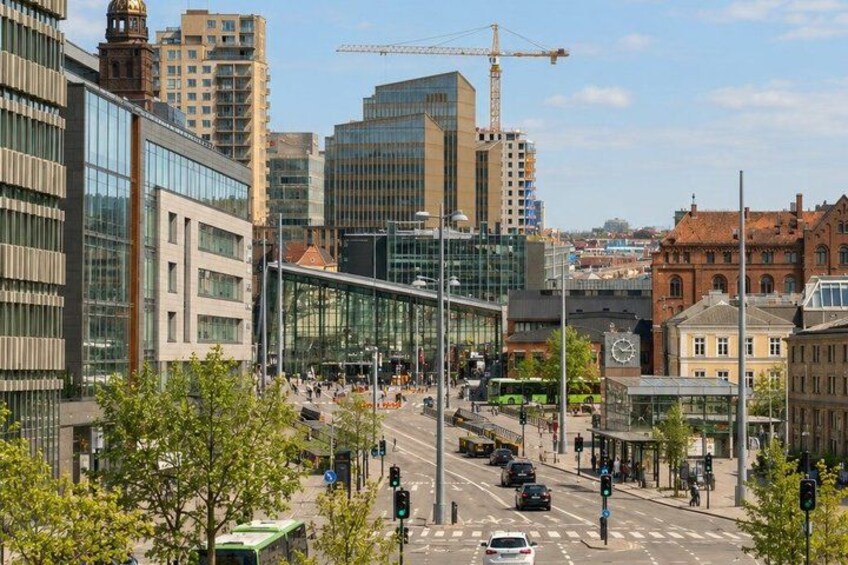 A city street with modern buildings, a bus stop, and a construction crane in the background. 4